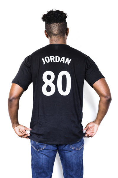 Back of Black male model wearing a June Jordan #80 black unisex tee